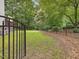 Fenced backyard with a green lawn and lush landscaping behind black metal fencing at 128 Castlewood Dr, Cary, NC 27511