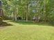 Large backyard features a manicured lawn, mature trees, and garden features at 128 Castlewood Dr, Cary, NC 27511