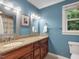 Bathroom with wood cabinets, double sinks, tile countertop, and blue walls at 128 Castlewood Dr, Cary, NC 27511