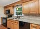 Close-up of kitchen counters with black appliances, wood cabinets, and a window view at 128 Castlewood Dr, Cary, NC 27511