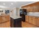 Kitchen with island, black appliances, wood cabinets, and connecting room view at 128 Castlewood Dr, Cary, NC 27511