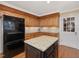 Kitchen with a center island, black appliances, granite countertops, and wood cabinets at 128 Castlewood Dr, Cary, NC 27511