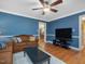 Inviting living room with hardwood floors, a brown sofa, and blue walls and ceiling fan at 128 Castlewood Dr, Cary, NC 27511