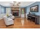 Cozy living room with brick fireplace, hardwood floors, and piano with a ceiling fan at 128 Castlewood Dr, Cary, NC 27511