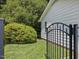 Side yard with metal gate, well-kept lawn, mature shrubbery, and vinyl siding at 128 Castlewood Dr, Cary, NC 27511