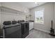 The laundry room features a dark washer and dryer, white shelving, a window, and a laundry sink at 140 Big Barn Dr, Wendell, NC 27591