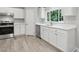 A view of a clean, white kitchen featuring stainless steel appliances, updated fixtures, and plenty of cabinet space at 160 Deer Tracks Dr, Wendell, NC 27591