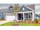 Landscaped front yard leads to a two-story home with a two-car garage, covered entryway, and blue siding at 1720 Pinecliff Ct, Fuquay Varina, NC 27526