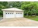 Two-car garage near a swing set and lush greenery, with a large concrete driveway at 2139 Race Track Rd, Burlington, NC 27215