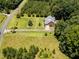 Aerial shot of home with lush landscaping, surrounded by dense trees and open fields at 2819 Russell Mcpherson Rd, Burlington, NC 27215