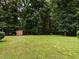 Backyard view of a utility shed with lean-to, and a large grassy yard at 2819 Russell Mcpherson Rd, Burlington, NC 27215