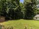 Wide shot of lush green backyard with thick tree line and shed in the distance at 2819 Russell Mcpherson Rd, Burlington, NC 27215