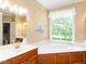 Bright bathroom featuring a jacuzzi tub with a large window and wood cabinets at 2819 Russell Mcpherson Rd, Burlington, NC 27215
