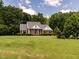 Inviting brick home with a manicured lawn and mature trees creating a serene setting at 2819 Russell Mcpherson Rd, Burlington, NC 27215