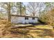 The backyard of the property shows the home and a grassy area with trees at 3013 Avery St, Raleigh, NC 27610