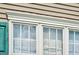 Close-up of a window featuring detailed trim, turquoise shutters, and a view of the sky reflecting in the glass at 402 Hearthstone Dr, Nashville, NC 27856