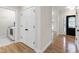 Hallway featuring hardwood floors, white closets, and entrance to laundry room at 4211 Norman Ridge Ln, Raleigh, NC 27613