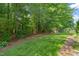 Green backyard with manicured lawn, mature trees, and landscape design at 4613 Moores Creek Rd, Durham, NC 27705