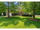Traditional brick home featuring mature landscaping, a manicured lawn, and shutters on the windows at 4613 Moores Creek Rd, Durham, NC 27705