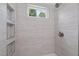 Updated shower showcasing light wood grain tile, recessed shelving, and a window at 502 S Eighth St, Mebane, NC 27302