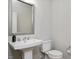 Clean powder room with modern pedestal sink, decorative mirror, and efficient toilet at 513 Brooks St, Wake Forest, NC 27587