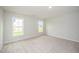 Bright, carpeted bedroom with two windows offering natural light and a view of the surrounding landscape at 66 W Emily Gardens Dr, Selma, NC 27576