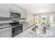 Bright kitchen features stainless steel appliances, granite countertops, and a double sink under a window overlooking the backyard at 66 W Emily Gardens Dr, Selma, NC 27576