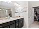 Bathroom featuring double sinks with granite countertops, dark cabinets, large mirror, and glass shower at 6928 Leesville Rd, Raleigh, NC 27613
