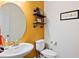 Charming half-bathroom with a large round mirror, pedestal sink, and bright colored wall at 6928 Leesville Rd, Raleigh, NC 27613