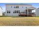 Rear view of the home's back exterior with deck, screened-in porch, and spacious grassy yard at 713 Ramsours Mill Dr, Holly Springs, NC 27540