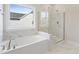 Bright bathroom featuring tub with tile surround and glass enclosed shower at 713 Ramsours Mill Dr, Holly Springs, NC 27540