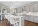 Bright kitchen features an island with bar stool seating, stainless appliances, gray cabinets, and stylish pendant lights at 713 Ramsours Mill Dr, Holly Springs, NC 27540