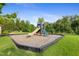 Playground with slide surrounded by green grass and trees on a sunny day at 713 Ramsours Mill Dr, Holly Springs, NC 27540