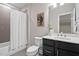 Cozy bathroom with a shower and tub combo, dark vanity, and painting and plant accessories at 728 Peninsula Forest Pl, Cary, NC 27519