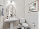 Stylish powder room with pedestal sink, round mirror, and elegant fixtures at 728 Peninsula Forest Pl, Cary, NC 27519
