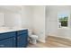 Bathroom with blue vanity, white countertop, toilet, and stand-up shower with wood-look floors at 74 W Emily Gardens Dr, Selma, NC 27576