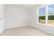 Bright bedroom features neutral carpet, white walls, and a window showcasing blue skies at 74 W Emily Gardens Dr, Selma, NC 27576