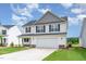 An inviting two-story home with white siding, a gray gable, and a spacious two-car garage at 74 W Emily Gardens Dr, Selma, NC 27576