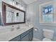 Bright bathroom with a large mirror, blue vanity, and a window providing natural light at 7917 Featherstone Dr, Raleigh, NC 27615