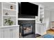 Living room fireplace with black brick, built-in cabinets, and a mounted television at 7917 Featherstone Dr, Raleigh, NC 27615