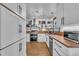 Bright kitchen featuring stainless steel appliances, butcher block countertops, open shelving, and white cabinets at 7917 Featherstone Dr, Raleigh, NC 27615