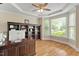 Bright home office featuring a large desk, built-in shelving, hardwood floors, and natural light from multiple windows at 10012 San Remo Pl, Wake Forest, NC 27587
