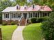 Inviting home with a red metal roof, gray siding, and a brick walkway leading to the front door at 101 Joel Ct, Cary, NC 27513