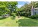 Lush backyard featuring mature trees, a greenhouse, and outdoor dining area for relaxation at 108 High St, Carrboro, NC 27510