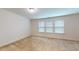 Bright bedroom featuring three large windows with blinds and neutral walls and carpet at 1365 Scholar Dr, Durham, NC 27703