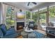 Cozy sunroom with a fireplace, TV, and plenty of natural light from the surrounding windows overlooking the landscaped yard at 1426 Kildaire Farm Rd, Cary, NC 27511