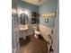 Stylish half bath with pedestal sink, wainscoting, decorative accents, and tiled flooring at 1831 Devonridge Dr, Fuquay Varina, NC 27526