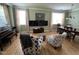 Open-concept living room featuring hardwood floors, two large windows, and comfortable seating at 1831 Devonridge Dr, Fuquay Varina, NC 27526