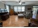 Cozy living room featuring hardwood floors, a comfortable sectional sofa, large windows, and stylish furnishings at 1831 Devonridge Dr, Fuquay Varina, NC 27526