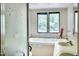 Bright bathroom features a large tub, window view of the yard, and decorative glass shower doors at 1907 Bivins St, Durham, NC 27707